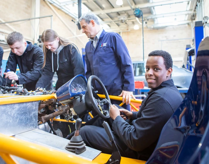Instructor and students collaborating on an engine repair project, focusing on mechanical details in a hands-on learning session. Instructor and students collaborating on an engine repair project, focusing on mechanical details in a hands-on learning session.